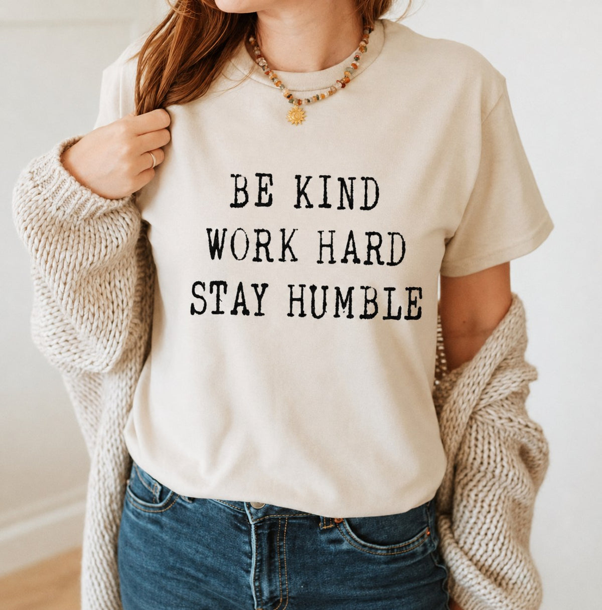Woman wearing a cream t-shirt printed with Be kind, Work hard, Stay humble