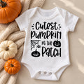 White baby bodysuit printed with Cutest Pumpkin in the Patch lettering, a spider web and jack-o'-lanterns