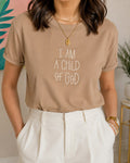 Woman wearing a tan t-shirt printed with the words I Am a Child of God