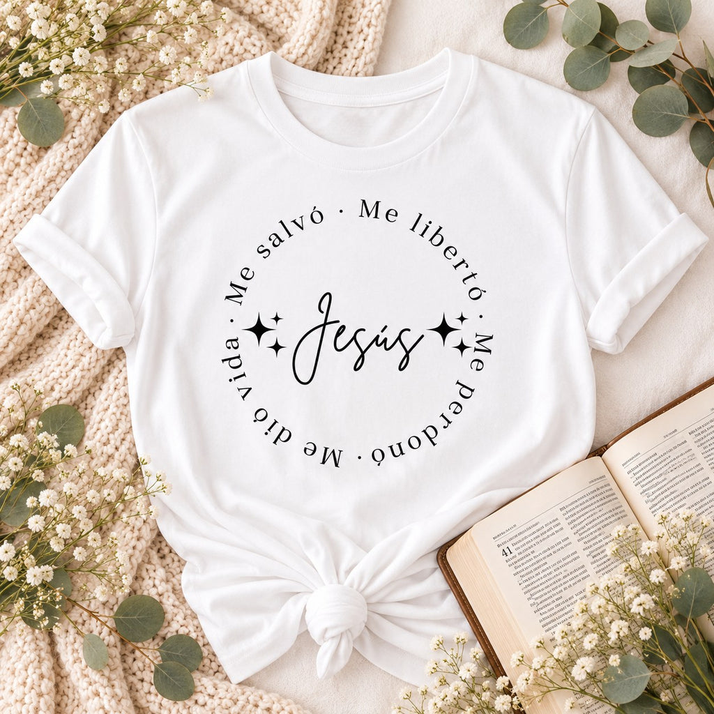 White t-shirt flat lay printed with Jesús in script surrounded by the words Me salvó, Me liberó, Me perdonó, Me dio vida