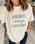 Woman wearing a cream oversized t-shirt printed with Kindness changes everything