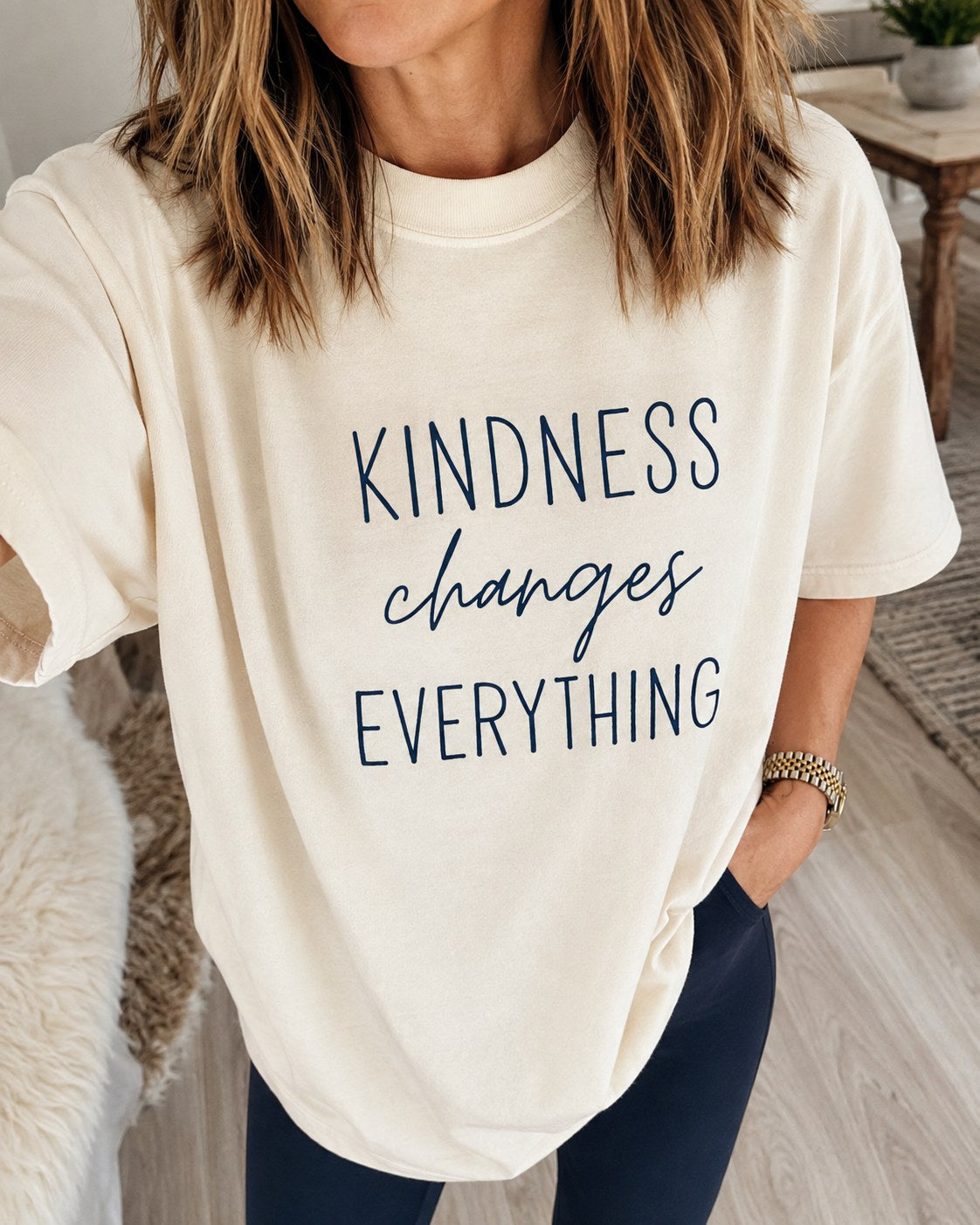 Woman wearing a cream oversized t-shirt printed with Kindness changes everything
