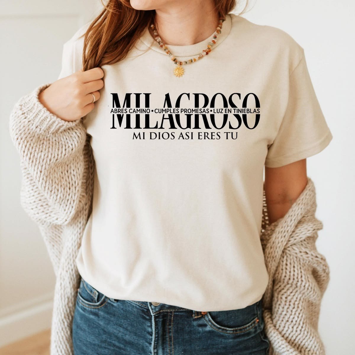 Woman wearing a cream t-shirt printed with MILAGROSO and Mi Dios así eres tú