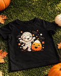 Black kids Halloween t-shirt with a happy mummy and a smiling candy corn