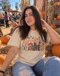 Woman wearing a cream t-shirt printed with Spooky Mama lettering, bats and a spider web